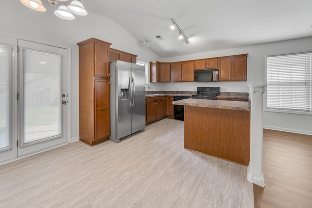 kitchen with light wood-style flooring, visible vents, vaulted ceiling, and black appliances