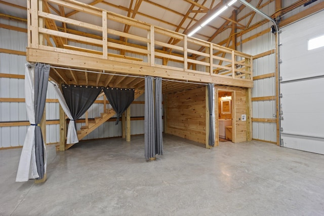 interior space featuring high vaulted ceiling, metal wall, and concrete floors