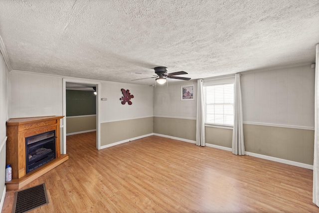 unfurnished living room with visible vents, a ceiling fan, light wood-style flooring, and a textured ceiling