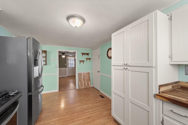 kitchen featuring visible vents, light wood-style floors, stove, ceiling fan, and stainless steel refrigerator with ice dispenser