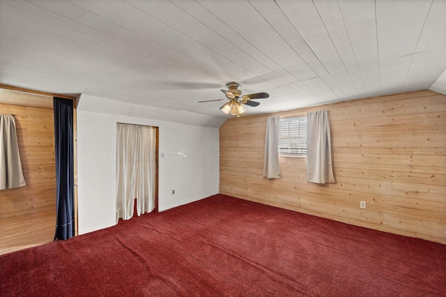 unfurnished room featuring carpet floors, ceiling fan, wood walls, and lofted ceiling