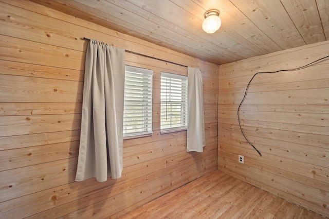 spare room featuring wooden walls and light wood-type flooring