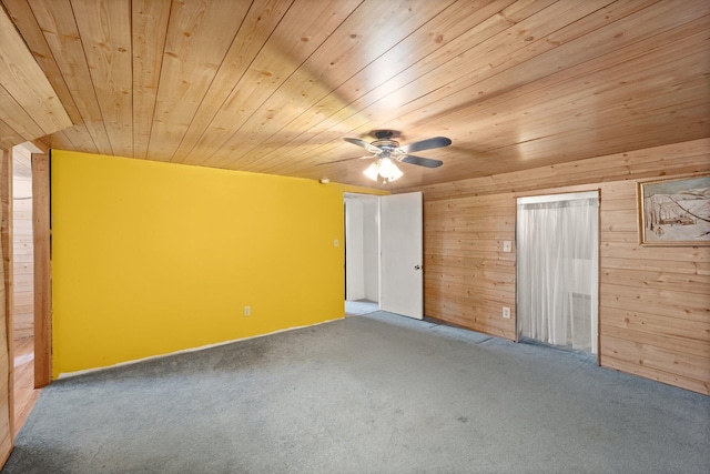 unfurnished bedroom featuring a ceiling fan, carpet, wooden walls, and wood ceiling