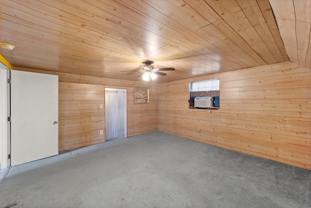 carpeted empty room featuring ceiling fan, wooden walls, and wooden ceiling