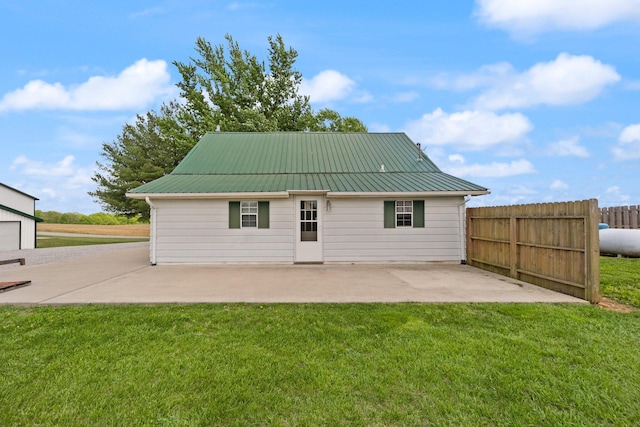 back of property with a lawn, a patio area, fence, and metal roof
