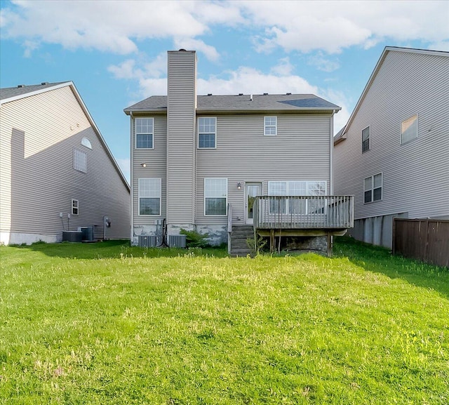 back of property with a wooden deck, a yard, central AC, and a chimney