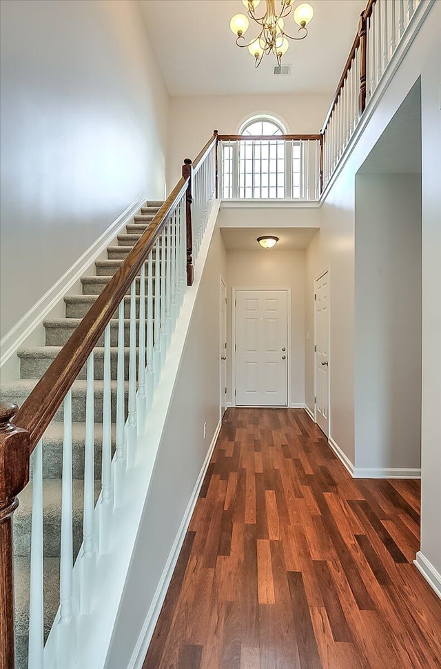 entrance foyer with stairs, a chandelier, wood finished floors, and baseboards