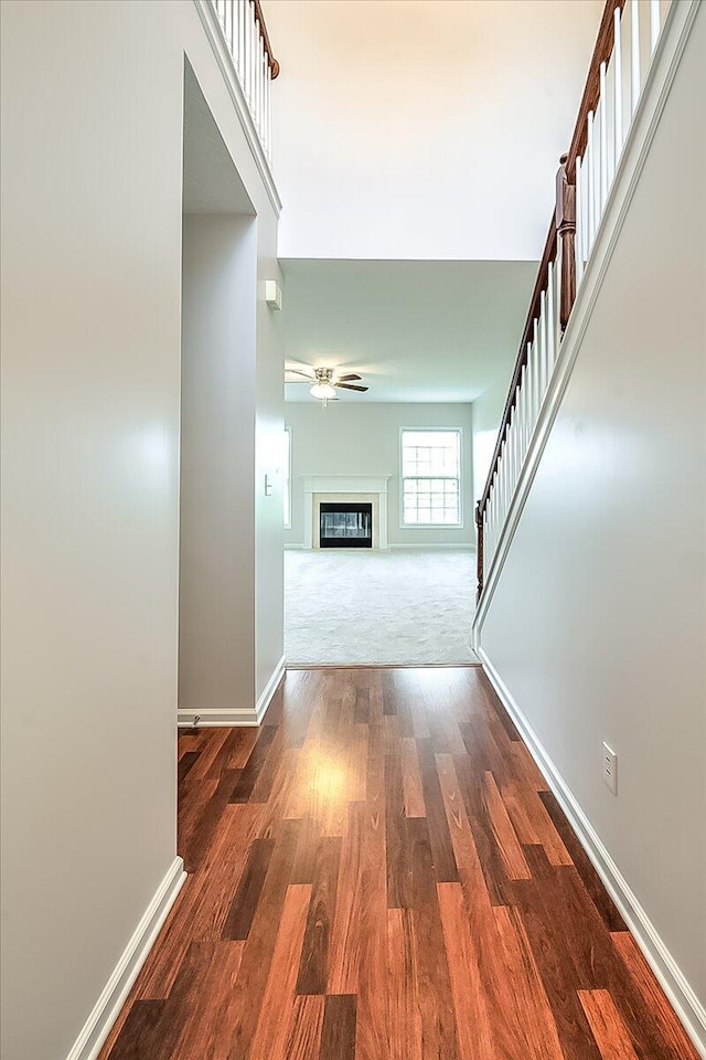 corridor with wood finished floors, stairs, and baseboards