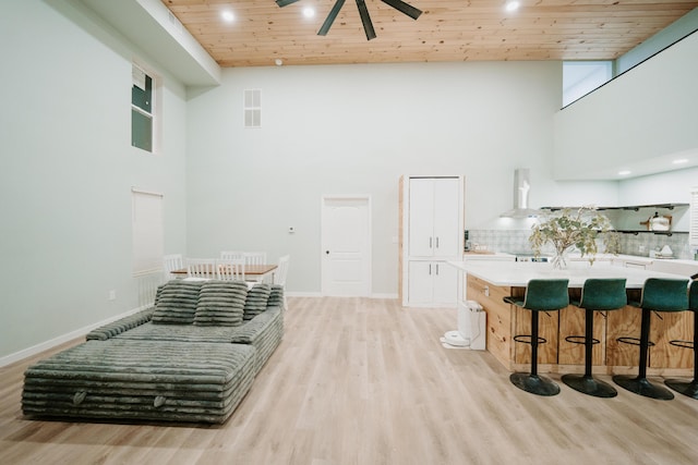 interior space with light wood-style flooring, a towering ceiling, wood ceiling, and a ceiling fan