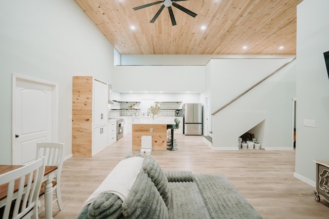 living room featuring a towering ceiling, recessed lighting, light wood-style floors, ceiling fan, and wooden ceiling