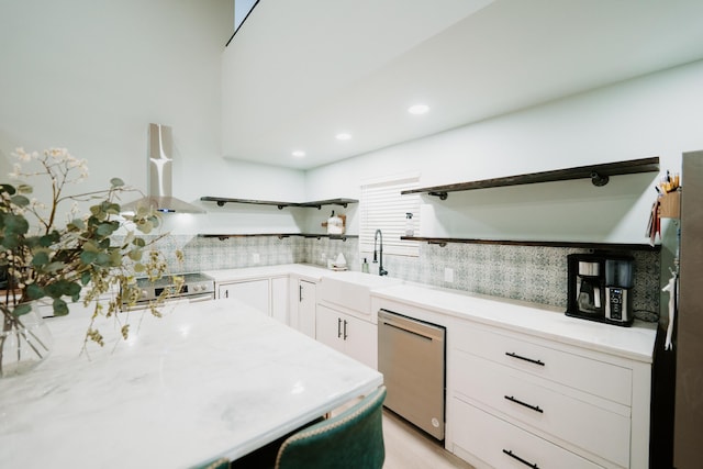 kitchen with wall chimney range hood, open shelves, a sink, stainless steel appliances, and light countertops