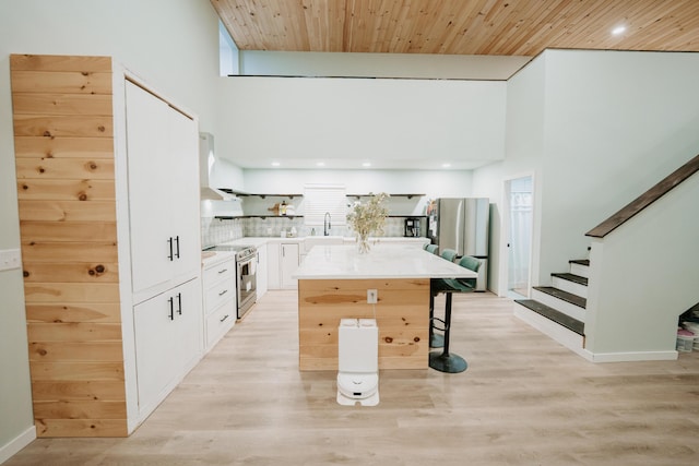 kitchen featuring a center island, a sink, stainless steel range with electric stovetop, a breakfast bar, and white cabinets