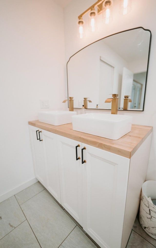 full bathroom featuring double vanity, tile patterned floors, baseboards, and a sink