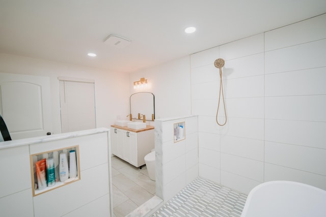bathroom with recessed lighting, a tile shower, tile patterned floors, and vanity