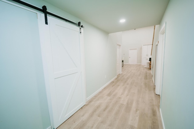 hall with a barn door, light wood-style flooring, baseboards, and recessed lighting