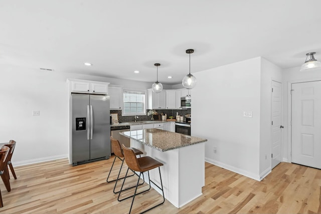 kitchen featuring recessed lighting, stainless steel appliances, light wood-style floors, baseboards, and tasteful backsplash