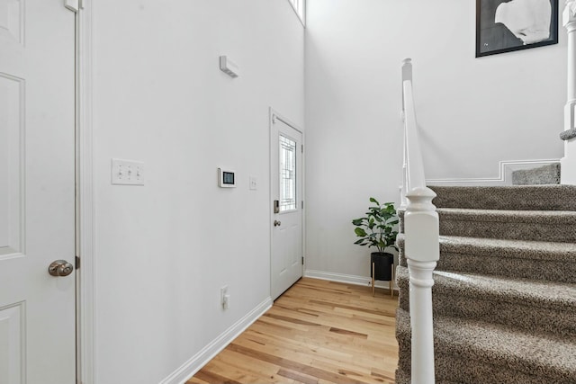 foyer entrance with stairway, baseboards, and light wood-style flooring