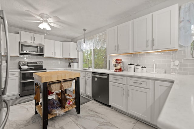 kitchen featuring marble finish floor, appliances with stainless steel finishes, a sink, and light countertops