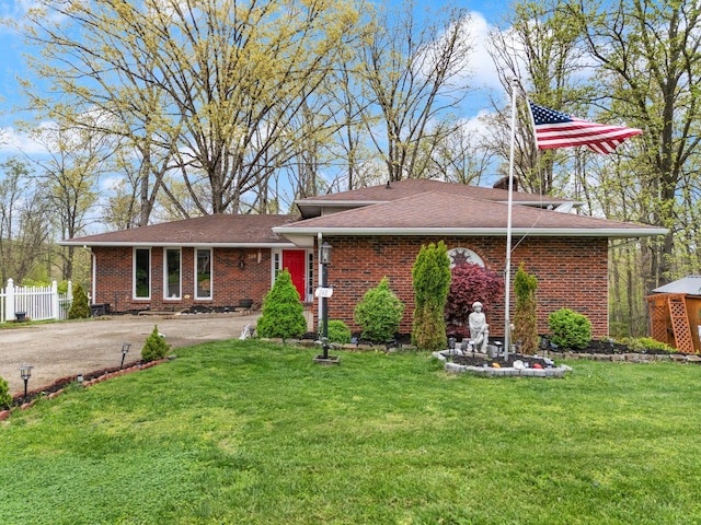ranch-style house featuring fence, aphalt driveway, brick siding, and a front yard