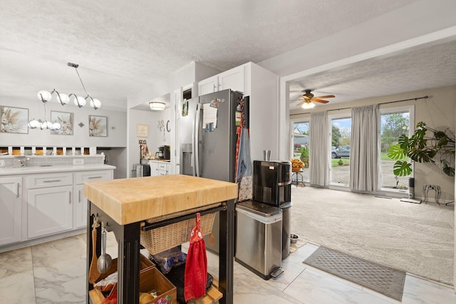kitchen with white cabinets, a textured ceiling, and marble finish floor