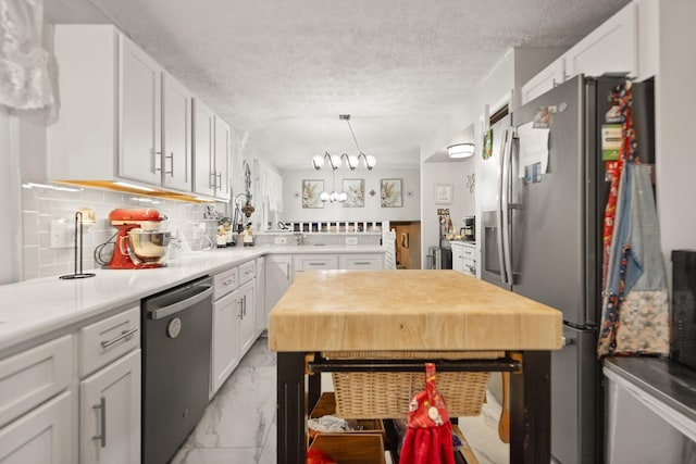 kitchen with white cabinets, stainless steel appliances, a textured ceiling, tasteful backsplash, and marble finish floor