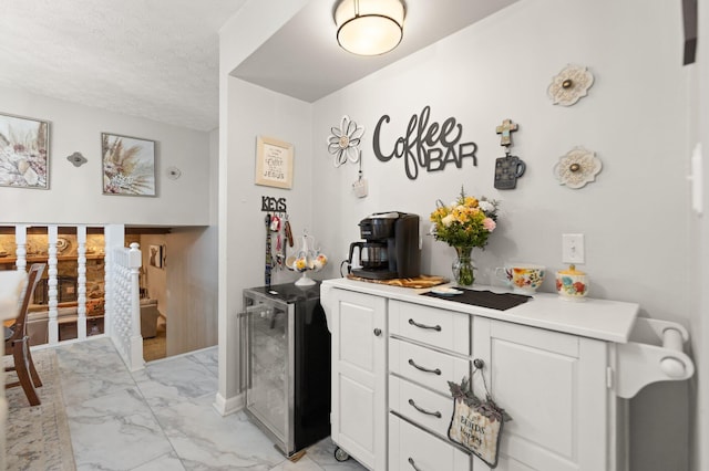 kitchen featuring marble finish floor, beverage cooler, white cabinets, and light countertops