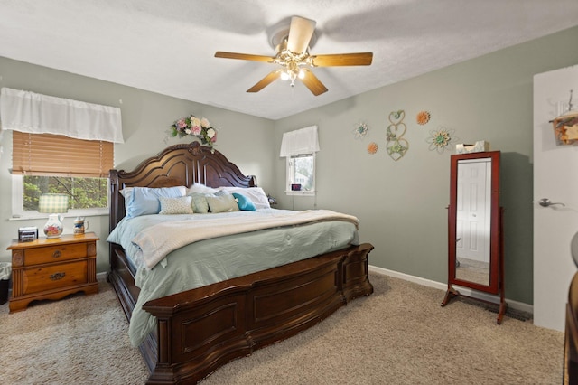 bedroom with ceiling fan, light carpet, multiple windows, and baseboards