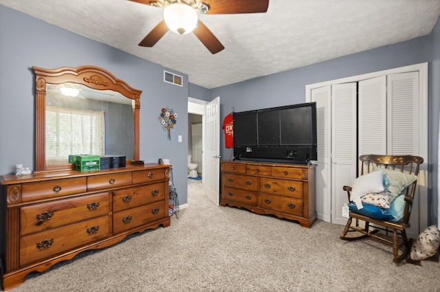 carpeted bedroom featuring visible vents, a textured ceiling, a closet, and ceiling fan