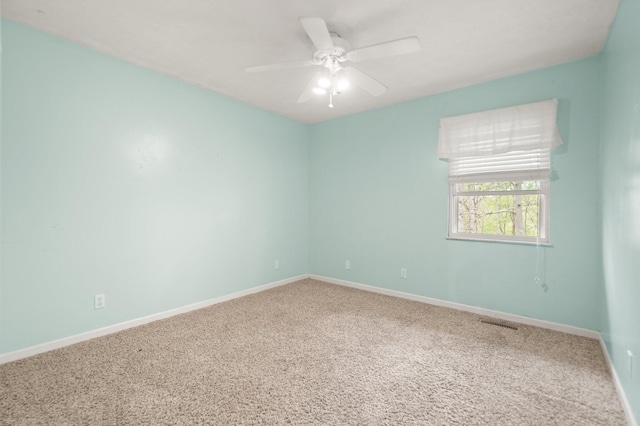 empty room with carpet floors, visible vents, baseboards, and ceiling fan