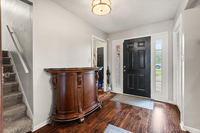 entryway featuring stairs, baseboards, a textured ceiling, and dark wood-type flooring