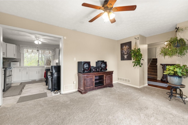 living area with visible vents, baseboards, ceiling fan, and stairs
