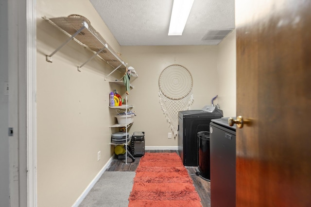 washroom featuring baseboards, visible vents, wood finished floors, washer and dryer, and laundry area