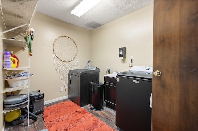 washroom featuring laundry area, washing machine and dryer, baseboards, dark wood-type flooring, and visible vents