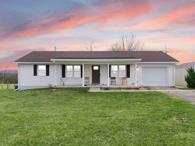 single story home with an attached garage, covered porch, a front lawn, and aphalt driveway