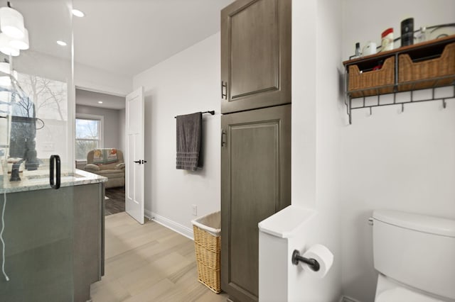 bathroom with recessed lighting, wood finished floors, toilet, and baseboards