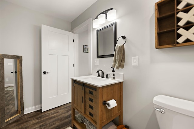 bathroom featuring baseboards, wood finished floors, vanity, and toilet