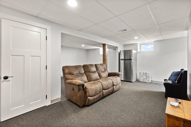 carpeted living room with baseboards, visible vents, and a drop ceiling