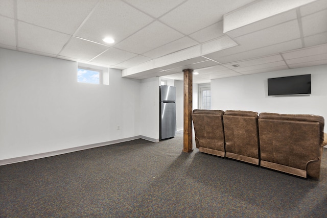 unfurnished living room with a paneled ceiling, baseboards, and dark carpet