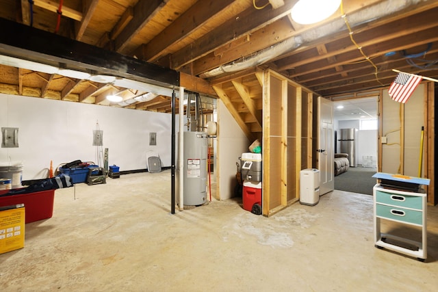 unfinished basement featuring water heater and freestanding refrigerator