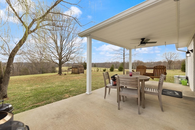 view of patio / terrace with a storage unit, an outdoor structure, outdoor dining space, and ceiling fan
