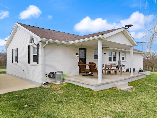 rear view of property featuring brick siding, a yard, a patio, and ceiling fan
