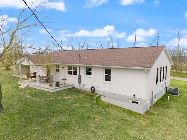 back of property with central AC unit, roof with shingles, a yard, and a patio