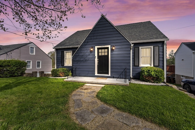 bungalow featuring a front lawn and roof with shingles