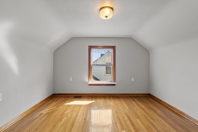 additional living space with vaulted ceiling, visible vents, light wood finished floors, and baseboards