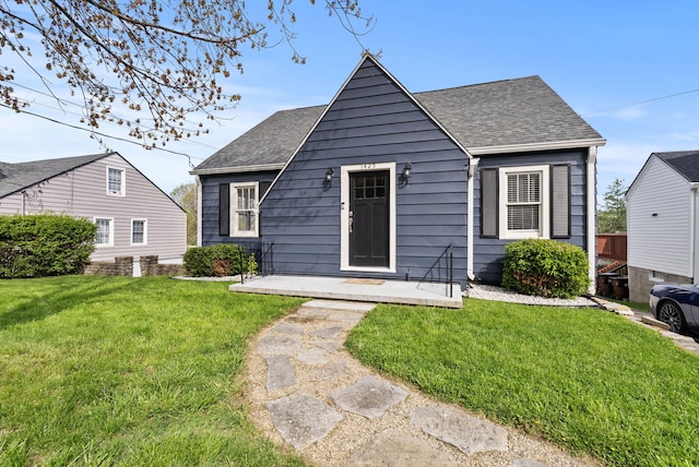 view of front of home with roof with shingles and a front yard
