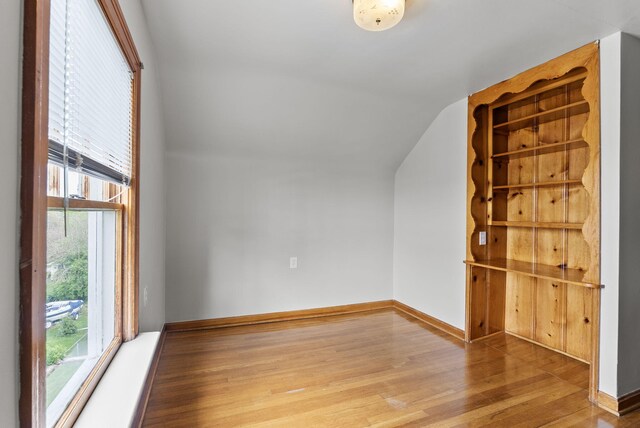 bonus room with baseboards, vaulted ceiling, wood finished floors, and a wealth of natural light