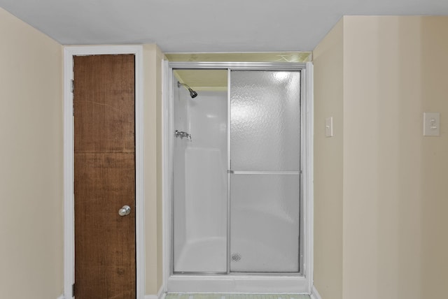bathroom with baseboards and a shower stall