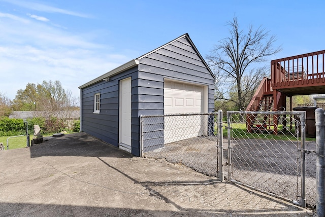 detached garage featuring fence, aphalt driveway, and a gate