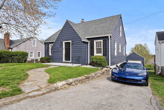 bungalow-style house with a shingled roof, a front yard, and a detached garage