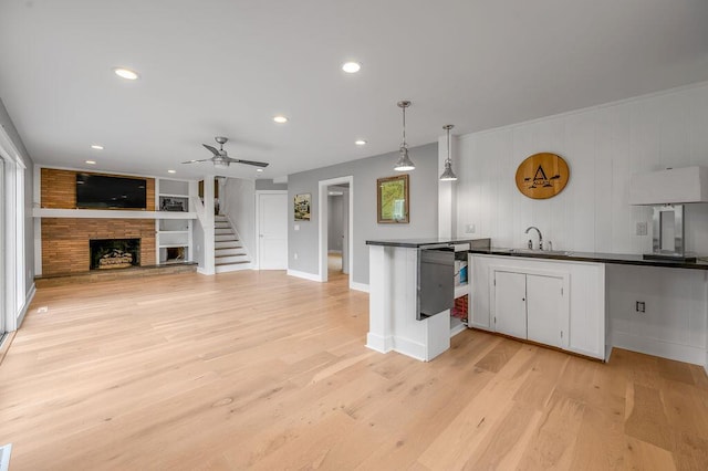 813 Westchester Dr, Lexington, KY 40502 - kitchen featuring dark countertops, a sink, light wood-type flooring, a fireplace, and white cabinetry